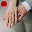 A woman's hand on top of a man's hand both wearing wedding rings with a red blood cell in the corner